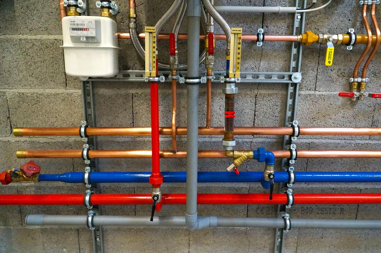 Gas meter and colour-coded pipework on a plant room wall