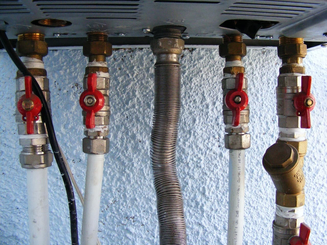 Isolation valves and flexible pipes under a wall-mounted boiler